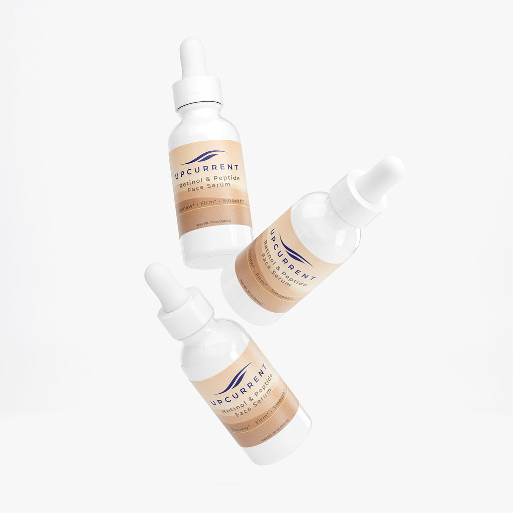 Three bottles of Upcurrent facial serum on a white background