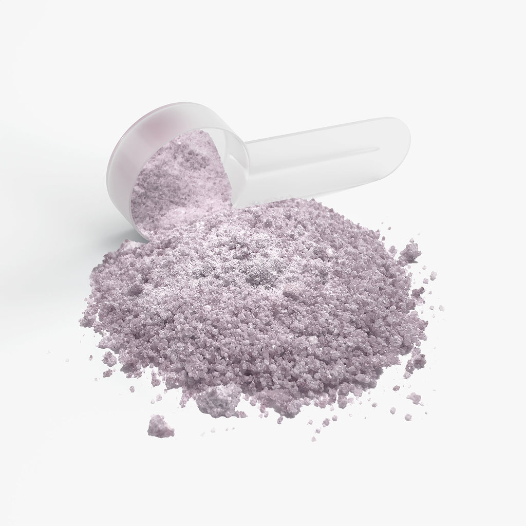 Purple powder spilling out of a white container on a light gray background